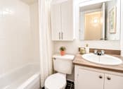 Thumbnail 11 of 17 - A white bathroom with a toilet, sink, and bathtub.
