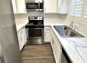 Thumbnail 12 of 29 - a small kitchen with white cabinets and stainless steel appliances