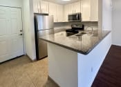 Thumbnail 8 of 29 - a kitchen with a granite counter top and a stainless steel refrigerator
