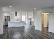 Thumbnail 33 of 52 - an open kitchen and living room with white cabinets and wood flooring