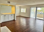 Thumbnail 3 of 40 - A spacious living room with wood flooring and white cabinetry.