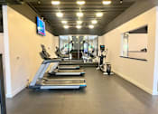 Thumbnail 35 of 40 - A gym with treadmills, elliptical machines, and a mirror.