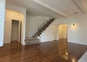 Thumbnail 32 of 60 - A spacious room with a staircase and wooden flooring.