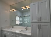 Thumbnail 38 of 60 - A bathroom with a large mirror, two sinks, and white cabinets.
