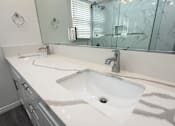 Thumbnail 35 of 60 - A white sink with a silver faucet is in the middle of a marble countertop.