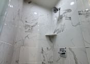 Thumbnail 36 of 60 - A shower area with a marble tile wall and a shower head.
