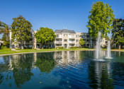 Thumbnail 2 of 30 - a fountain in the middle of a pond with apartment buildings in the background