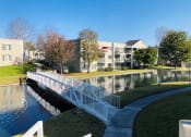 Thumbnail 11 of 30 - a white bridge over a pond with apartment buildings in the background