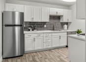 Thumbnail 32 of 32 - A modern kitchen with a stainless steel refrigerator and white cabinets.