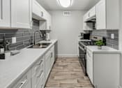 Thumbnail 30 of 32 - A kitchen with white cabinets and a black stove top oven.