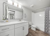 Thumbnail 31 of 32 - A white bathroom with a sink, toilet, and a shower.