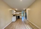 Thumbnail 8 of 9 - an empty living room and kitchen with wood floors