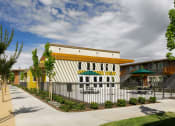 Thumbnail 9 of 11 - a building with a white and yellow facade and a black and white fence in front of it