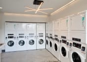 Thumbnail 9 of 17 - a row of washing machines and dryers in a laundry room