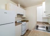 Thumbnail 3 of 15 - A kitchen with a white fridge, stove and sink.