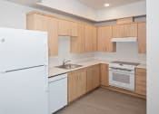 Thumbnail 11 of 17 - a kitchen with white appliances and wooden cabinets