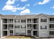 Thumbnail 8 of 15 - A large apartment complex with multiple balconies and doors.