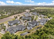 Thumbnail 10 of 15 - A bird's eye view of a residential complex surrounded by greenery and a highway.