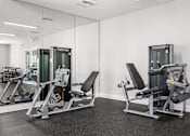 Thumbnail 12 of 15 - A gym with a mirror and two weight machines.