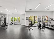 Thumbnail 13 of 15 - A spacious gym with a variety of equipment and a view of trees outside the windows.