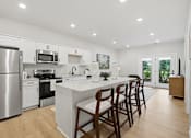 Thumbnail 21 of 25 - A kitchen with a white island and wooden chairs.