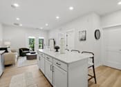 Thumbnail 8 of 25 - A kitchen with white cabinets and a white island.