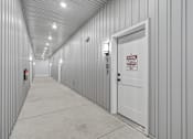 Thumbnail 11 of 25 - A long hallway with a door that has a sign on it.