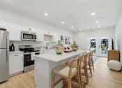 Thumbnail 18 of 25 - A modern kitchen with a white island and wooden chairs.