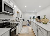 Thumbnail 19 of 25 - A modern kitchen with white cabinets and black appliances.