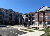 Thumbnail 2 of 20 - Apartment complex with a parking lot in front.