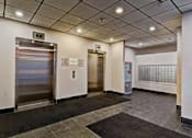 Thumbnail 72 of 72 - A hallway with two elevators and a calendar on the wall.