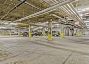 Thumbnail 5 of 42 - A parking garage with cars parked and yellow poles.