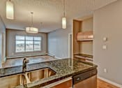 Thumbnail 60 of 72 - A kitchen with a granite countertop and stainless steel appliances.