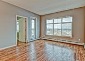 Thumbnail 55 of 72 - A room with wooden floors and a large window overlooking a parking lot.