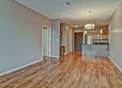 Thumbnail 53 of 72 - A room with wooden flooring and a kitchen area in the background.