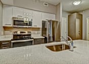 Thumbnail 39 of 72 - A kitchen with a sink, stove, and refrigerator.