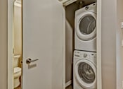 Thumbnail 25 of 72 - A white door opens to a small laundry room with a washer and dryer.