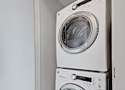 Thumbnail 11 of 27 - Two white front loading washing machines in a small laundry room.