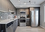 Thumbnail 15 of 27 - A modern kitchen with stainless steel appliances and wooden cabinets.