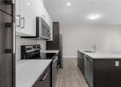 Thumbnail 7 of 25 - a renovated kitchen with white counter tops and stainless steel appliances