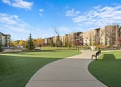 Thumbnail 21 of 72 - a park with green grass and buildings in the background