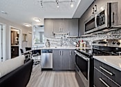 Thumbnail 14 of 27 - A modern kitchen with dark wood cabinets and stainless steel appliances.
