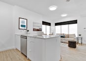 Thumbnail 49 of 78 - A modern kitchen with white cabinets and appliances, a framed picture on the wall, and a large window with blinds.