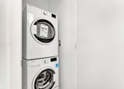 Thumbnail 53 of 78 - A white front loading washing machine with a black door is in a white room.