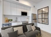Thumbnail 58 of 78 - A modern living room with a grey couch and a kitchen area in the background.