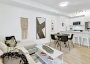 Thumbnail 14 of 78 - A modern living room with a white sofa, a coffee table, and a dining area in the background.