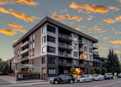 Thumbnail 65 of 78 - A large apartment building with cars parked in front.