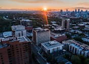 Thumbnail 63 of 78 - A cityscape with buildings and a sunset in the background.