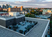 Thumbnail 72 of 78 - A rooftop patio with a table and chairs overlooks a city skyline.