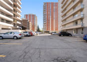 Thumbnail 30 of 33 - an empty parking lot with tall buildings on either side and cars parked